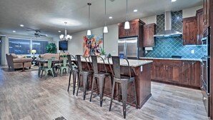 Una cocina moderna con armarios de madera, electrodomésticos de acero inoxidable e iluminación colgante.