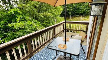 A balcony with a patterned floor, a table with chairs, and a large umbrella.