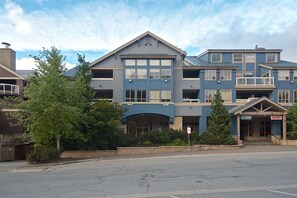 A multi-story hotel with a central entrance, large windows, and a covered outdoor area. - Whistler Village - Pool - Hot tub - walk to lifts - Tyndall Stone Lodge - BBQ (whistler)