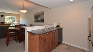 Una cocina moderna con armarios de madera, lavavajillas incorporado y comedor con mesa y sillas.