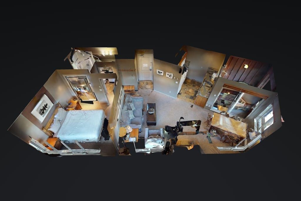 Panoraamanäkymä hotellihuoneeseen, jossa on sänky, oleskelualue ja pieni keittiö.