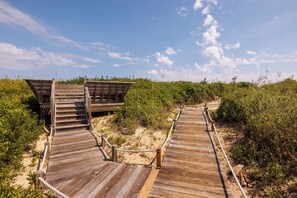 A wooden boardwalk leading to a wooden structure with a ramp.
