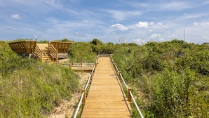 Une promenade en bois menant à une structure également en bois, accessible par des marches.
