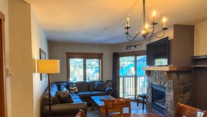 A cozy living room with a fireplace, a dining table, and a sofa.