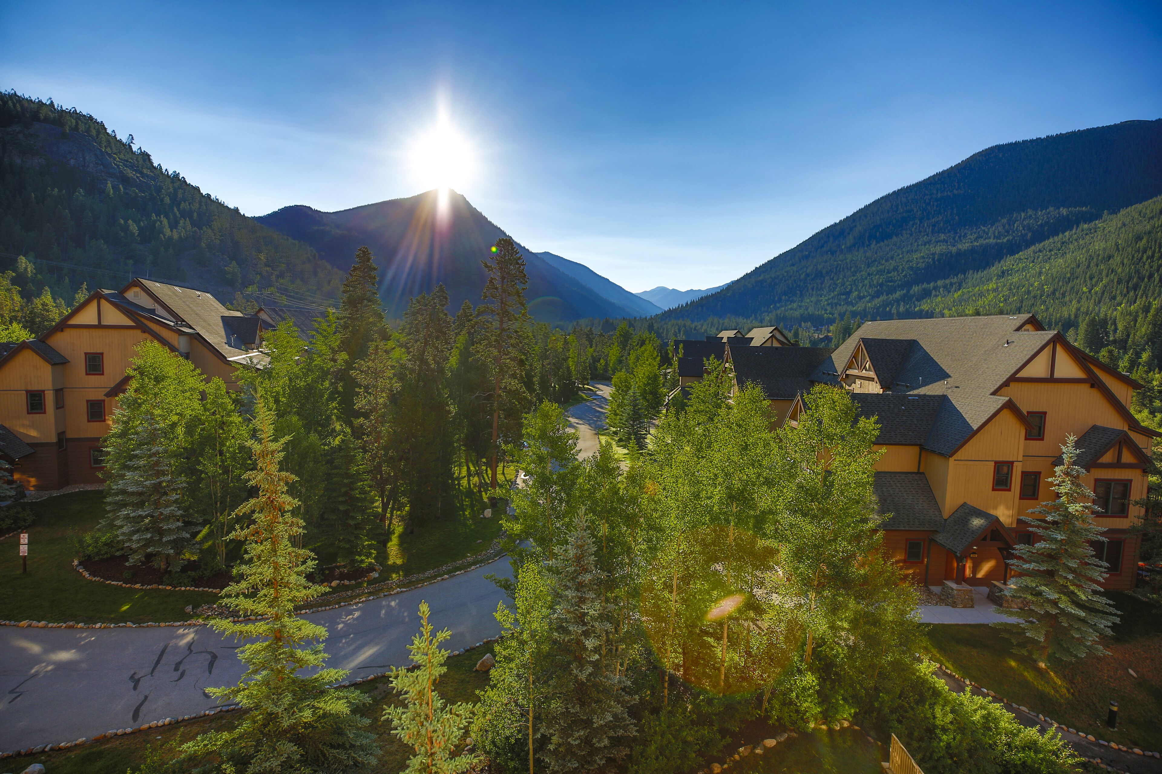 A residential area with houses surrounded by mountains and trees.