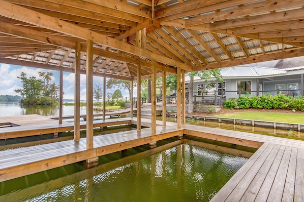 A wooden deck with a pool, surrounded by a covered area with metal beams and columns.