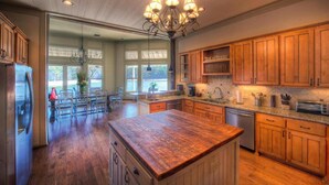 Une cuisine spacieuse avec des meubles en bois, un îlot central et un lustre.