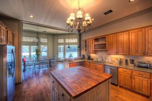 A spacious kitchen with wooden cabinets, a central island, and a chandelier.