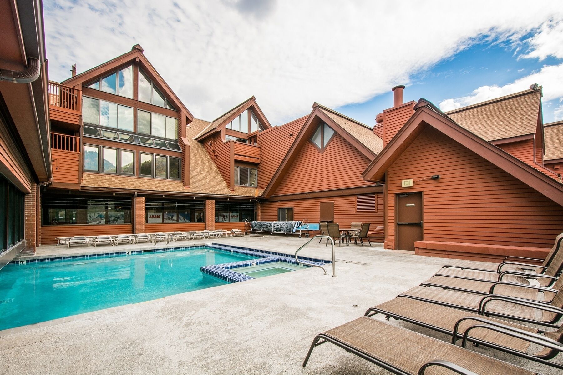 A pool area with lounge chairs and a clear sky.