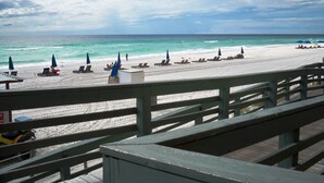 A beach with a wooden boardwalk, beach chairs, and umbrellas.