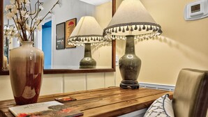 Une table en bois sur laquelle se trouvent un vase et une lampe, un magazine et un miroir qui reflète la lumière de la lampe.