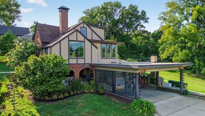 Une maison à deux étages dotée d’un patio couvert, d’une cheminée en briques et d’une pelouse bien entretenue.