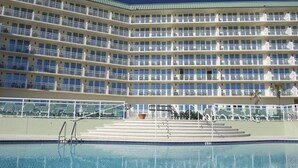 A multi-story hotel with balconies, a swimming pool, and outdoor seating.