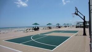 An outdoor basketball court with a view of the beach and ocean.