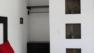 A room with a black wardrobe, a red pillow, and three wall-mounted planters with small plants.