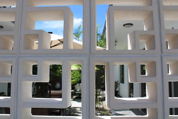 A white metal grid structure with a view of outdoor seating and palm trees.