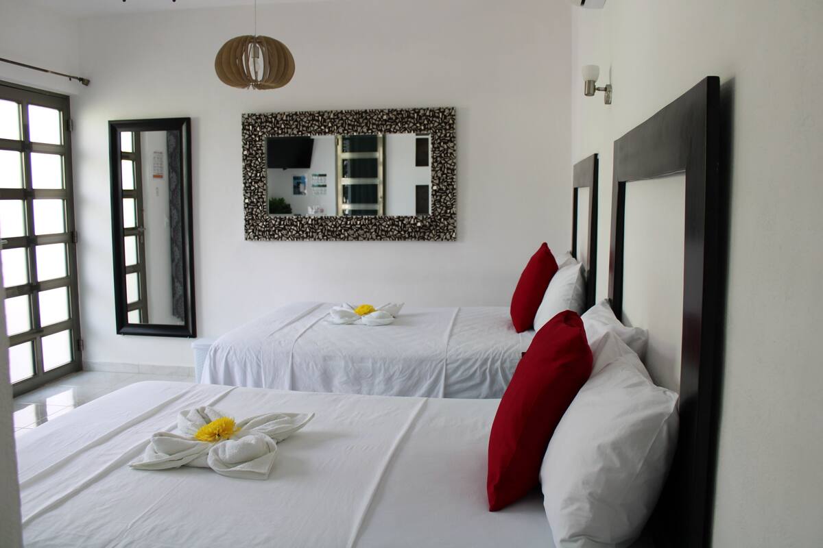 A hotel room with two beds, a large mirror, and a view of the outside.