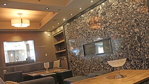 A modern interior with a stone wall, a wooden dining table, and seating arrangements. - Stunning Penthouse Suite (Canmore)