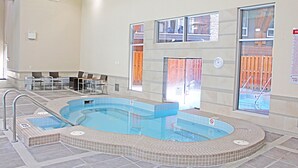 A hotel swimming pool with a hot tub, seating area, and a view of the outside. - Stunning Penthouse Suite (Canmore)