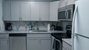 A modern kitchen with grey cabinets, a stainless steel refrigerator, a microwave, and a dishwasher. - Cute and affordable 3BDR duplex in Overland Park for up to 12 people! (Overland Park)