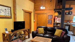Una sala de estar acogedora con un sofá de cuero, una mesa de centro de madera y un televisor de pantalla plana.