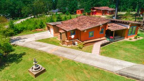 Una propiedad residencial con techo de tejas rojas, un camino de entrada y un pequeño jardín con una fuente.