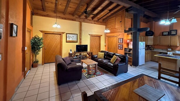 Un salón amplio con techo de madera, televisor y mesa de comedor.