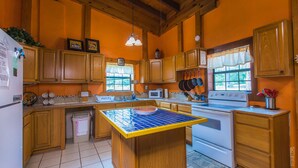 Una cocina con armarios de madera, una isla central, una estufa y un microondas.
