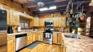 A kitchen with wooden cabinets, a microwave, an oven, and a sink. - Spotted Fawn Cabin - Serenity and luxury await you (Shenandoah)