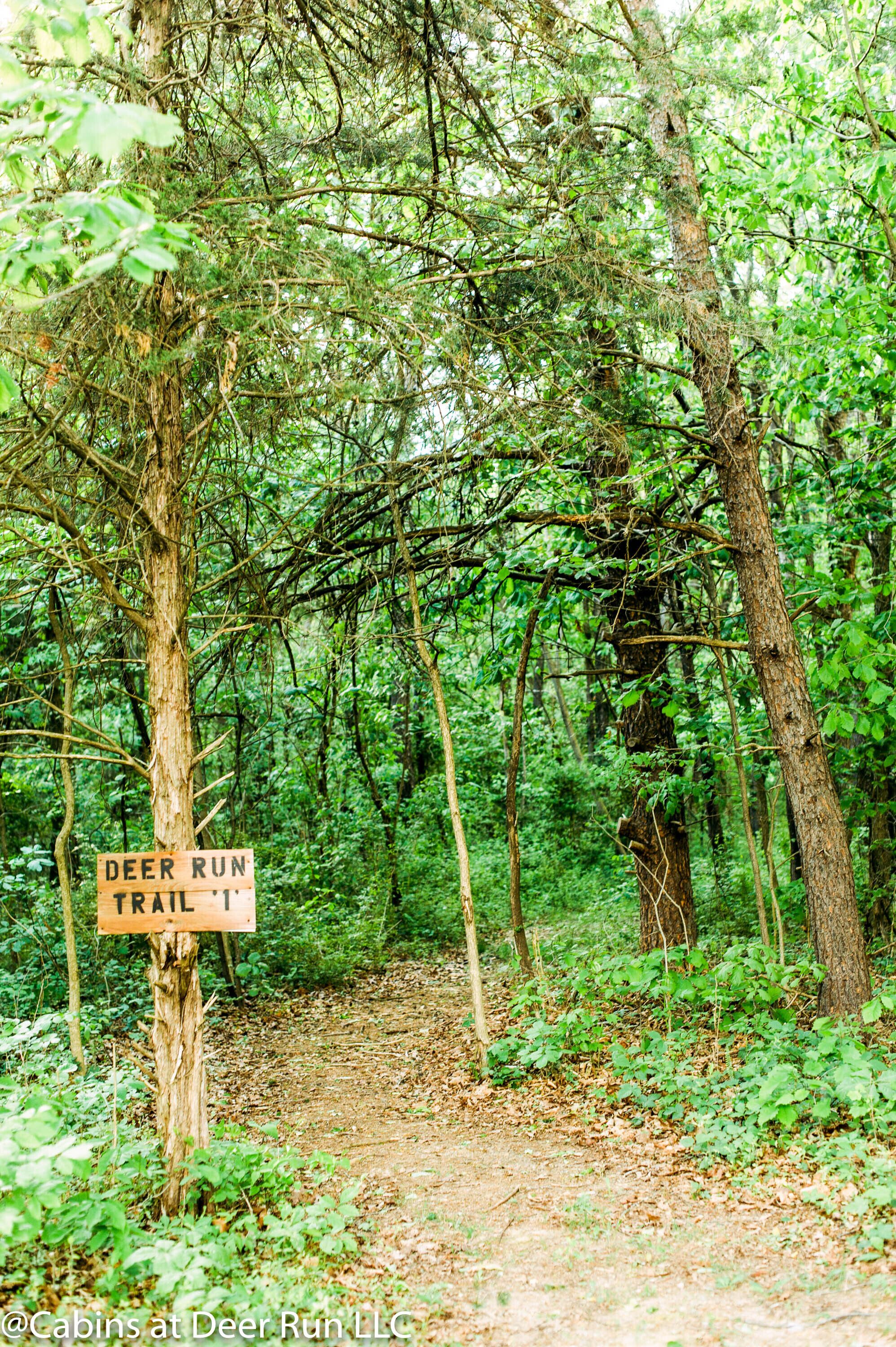 Sentiero boschivo con un cartello che indica 'Deer Run Trail 1'.