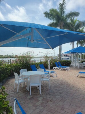 Eine Terrasse mit Tischen, Stühlen, Sonnenschirmen und Palmen.