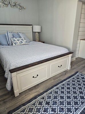 Une chambre à coucher avec un lit, une table de chevet, une lampe et un tapis à motifs.