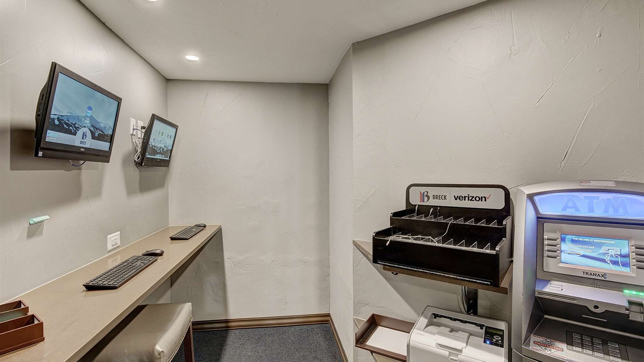Habitación de hotel con escritorio, dos monitores, un cajero automático e impresora.