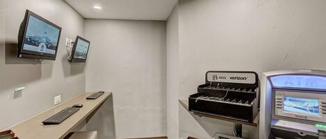 Habitación de hotel con escritorio, dos monitores, un cajero automático e impresora.
