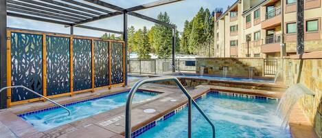 Zona de piscina con varios jacuzzis y una cascada.