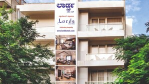 Un immeuble à plusieurs étages, sur lequel on peut voir une enseigne indiquant « Lords Eco Inn », avec une architecture moderne, des balcons et une entrée bien visible.