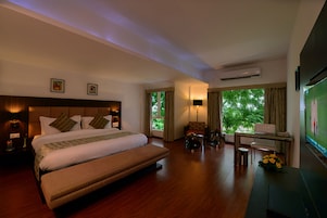 A hotel room with a large bed, a desk, a chair, and a TV.