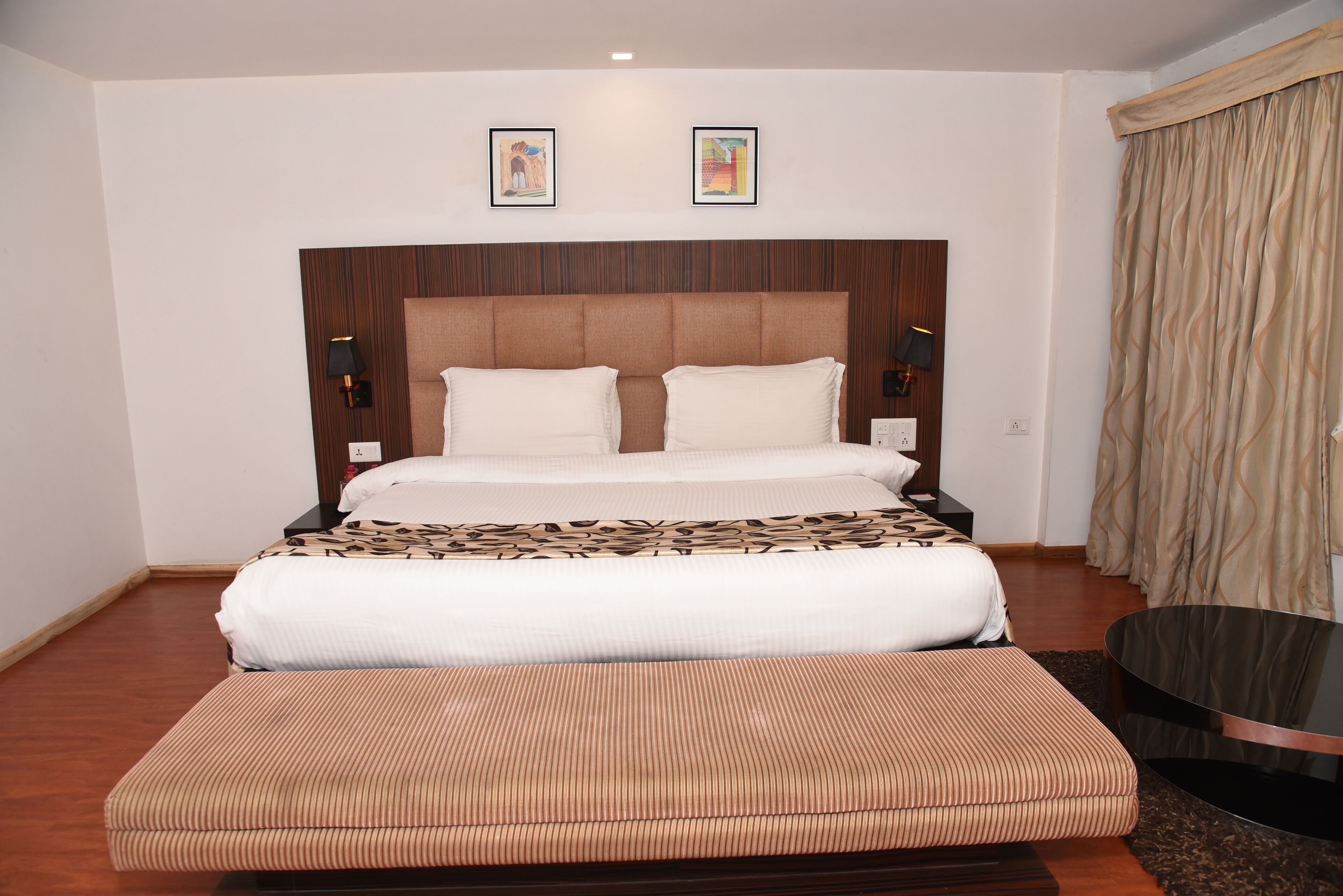 A hotel room with a large bed, a bedside table, a lamp, and a curtain.
