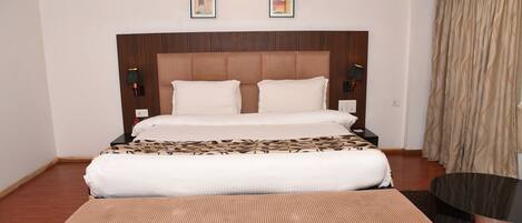 A hotel room with a large bed, a bedside table, a lamp, and a curtain.