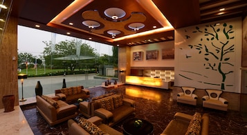 A lobby with a reception desk, seating area, and a wall with a tree mural.
