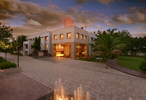 A modern hotel with a central courtyard, a fountain, and a well-lit entrance.