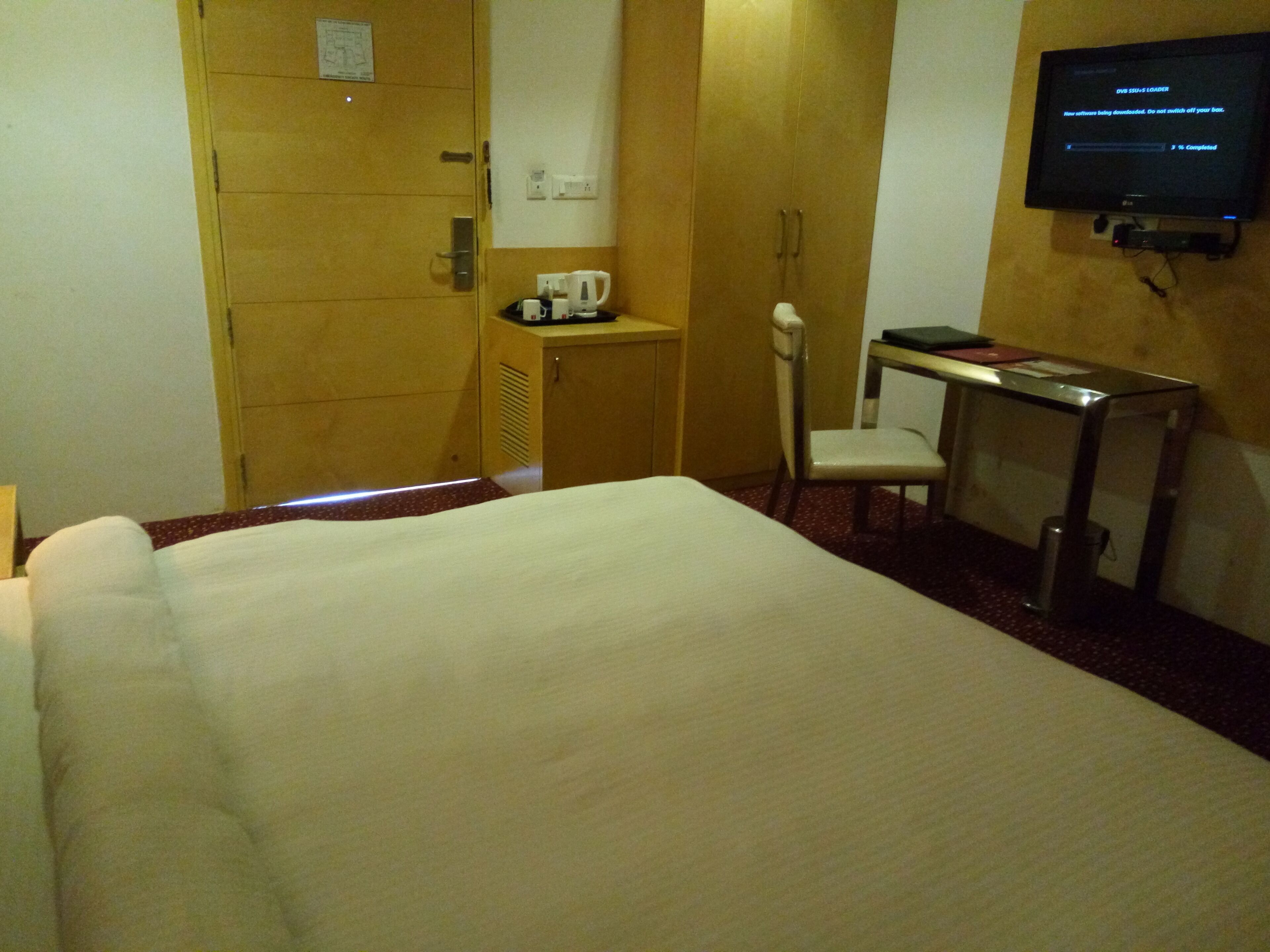 A hotel room with a bed, a desk with a chair, a television, and a coffee maker.