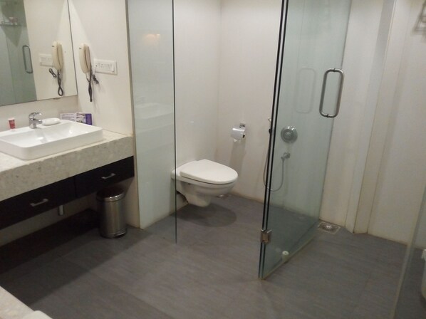 Un baño moderno con ducha envuelta en vidrio, inodoro blanco y lavabo con encimera de mármol.