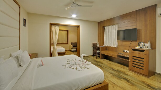 Una habitación de hotel con cama, escritorio, silla, televisor y ventilador de techo.