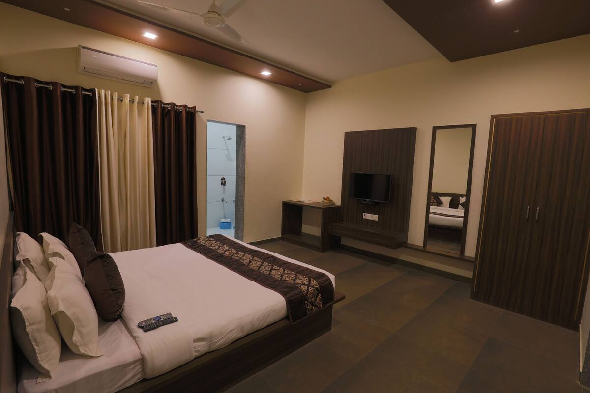 Een hotelkamer met een bed, een televisie, een kledingkast, een spiegel en een badkamers deur.