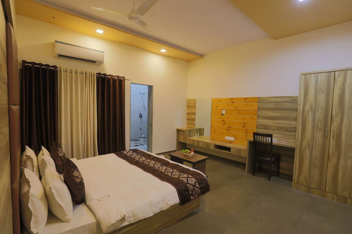 Een hotelkamer met een bed, een bureau, een stoel, een airconditioning en een kledingkast.