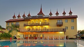 Ein Hotel mit großem Pool, mehreren Balkonen und einem markanten architektonischen Stil mit spitz zulaufenden Dächern.