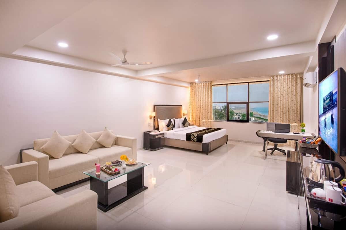 A modern hotel room with a sofa, a bed, a desk, and a TV.