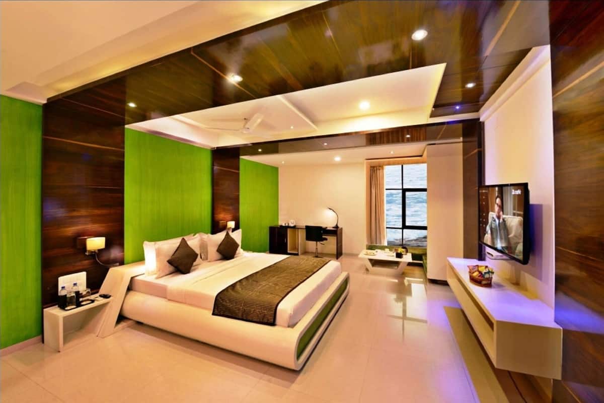 A modern hotel room with a large bed, a desk, a TV, and a view of the outdoors.