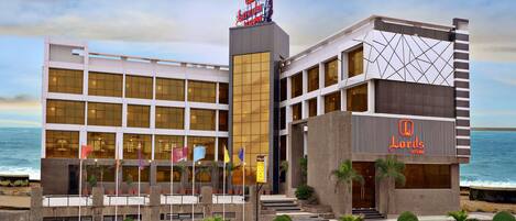 A hotel with a modern design, featuring a prominent 'Lords' sign, large windows, and a view of the ocean.